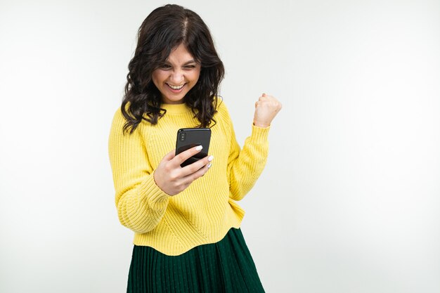 Jeune femme brune réussie avec un smartphone dans ses mains sur un blanc avec copie espace