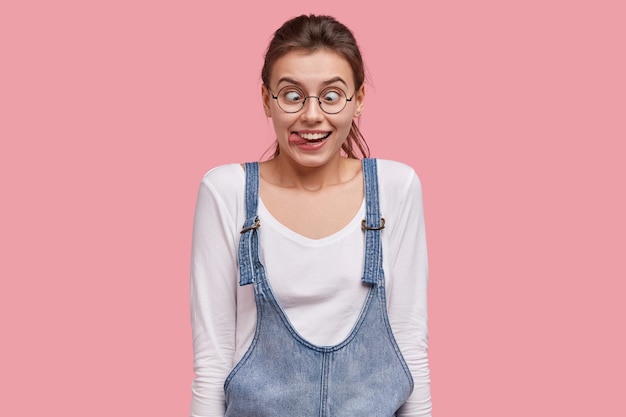 Jeune femme brune en salopette en denim