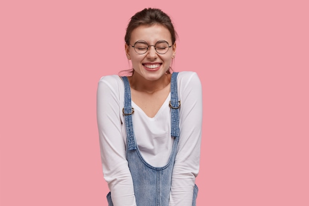 Jeune femme brune en salopette en denim