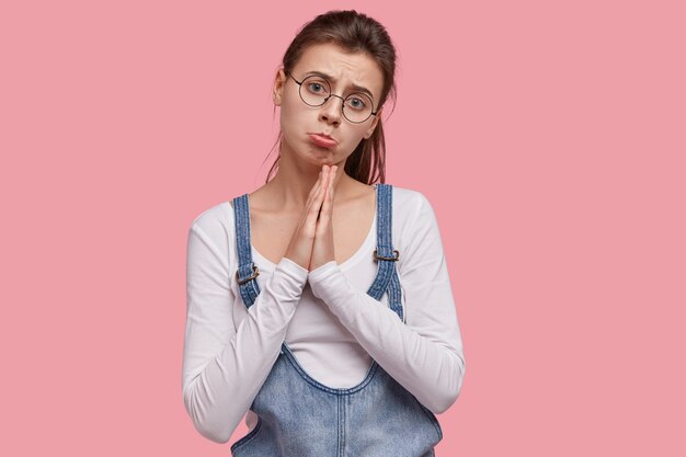 Jeune femme brune en salopette en denim