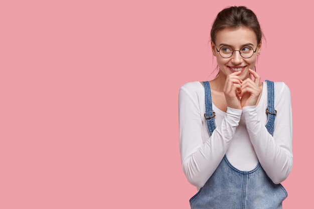 Jeune femme brune en salopette en denim