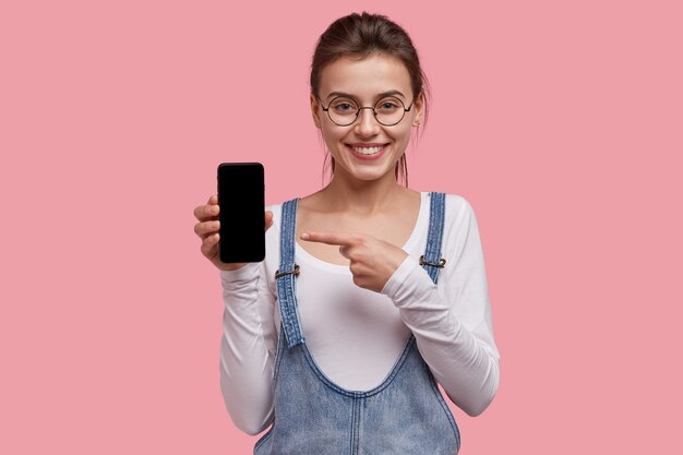 Jeune femme brune en salopette en denim