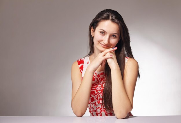 Jeune femme brune souriante à la caméra contre le blanc