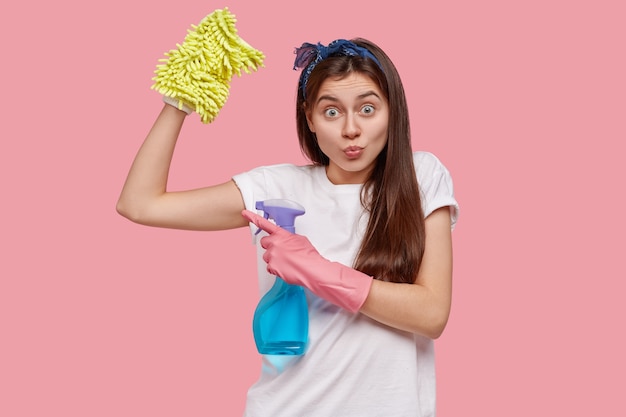 Jeune femme brune tenant des produits de nettoyage