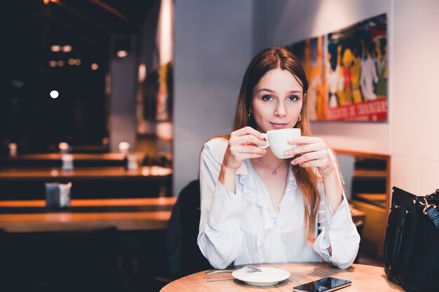 Jeune femme buvant au café