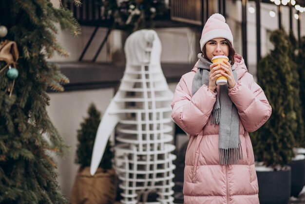 Jeune femme buvant du café à l'extérieur de la rue d'hiver