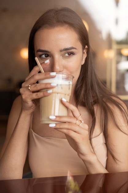 Photo gratuite jeune femme buvant du café glacé