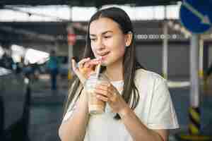 Photo gratuite une jeune femme buvant du café sur le parking