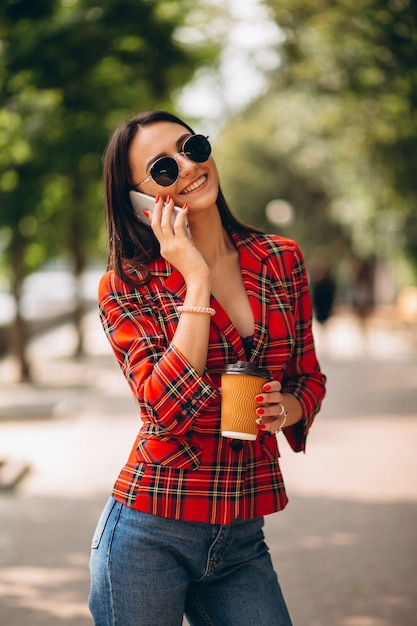 Jeune femme buvant du café et parlant au téléphone