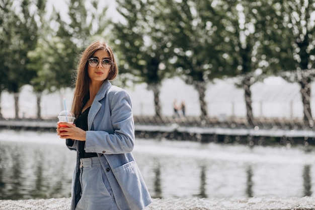 Jeune femme buvant du thé glacé dans le parc