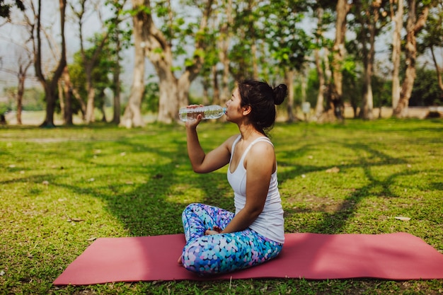 Jeune femme buvant de l&#39;eau après le yoga