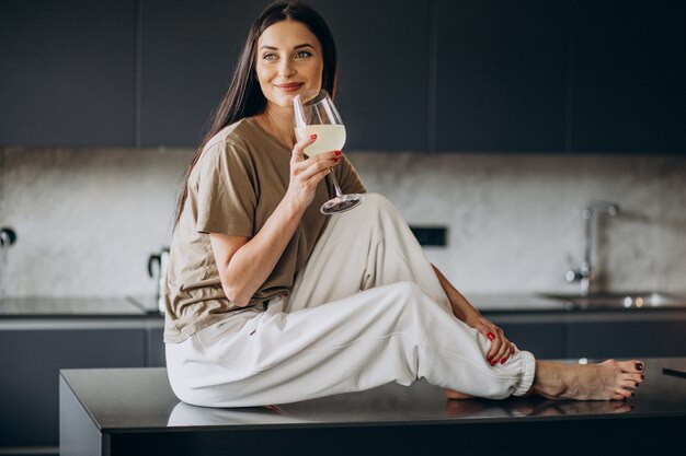 Jeune femme buvant de la limonade de verre à la cuisine