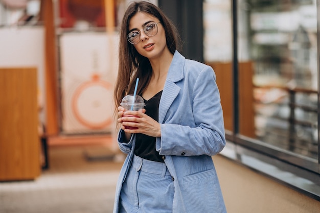 Jeune femme buvant un verre de glace à l'extérieur de la rue