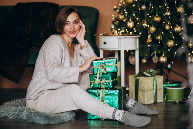 Jeune femme avec un cadeau de Noël près du sapin de Noël