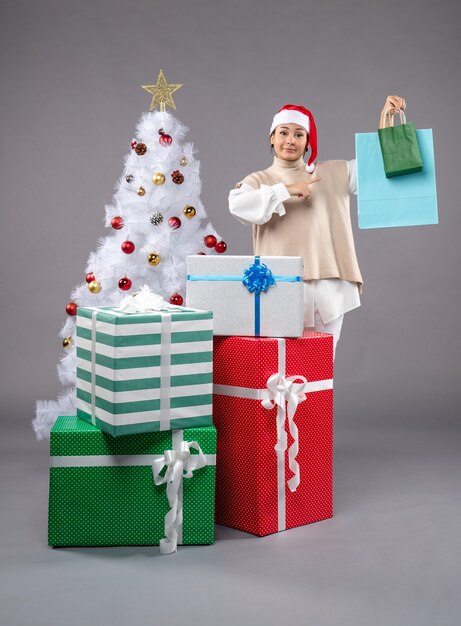 jeune femme avec des cadeaux de Noël sur fond gris