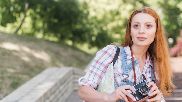 Jeune femme avec une caméra rétro dans le parc