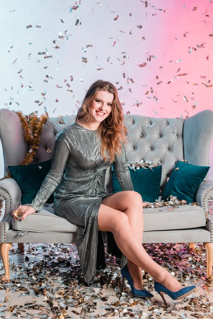 Jeune femme sur un canapé avec un verre de champagne