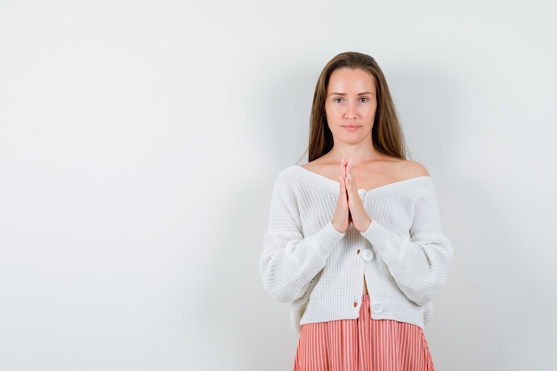 Jeune femme en cardigan et jupe main dans la main en signe de prière isolé