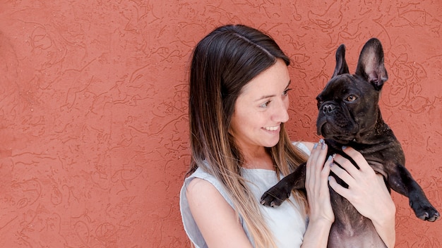 Photo gratuite jeune femme caressant son bouledogue français