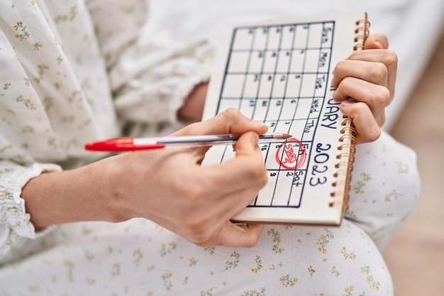 Photo gratuite jeune femme caucasienne écrivant le mot de départ sur le calendrier dans la chambre