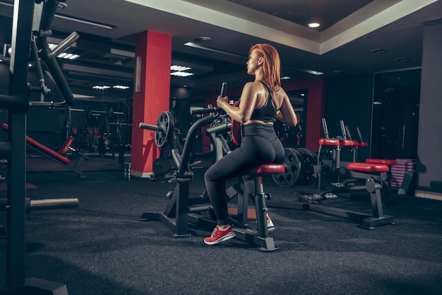 Jeune femme caucasienne musclée pratiquant dans une salle de sport avec équipement.