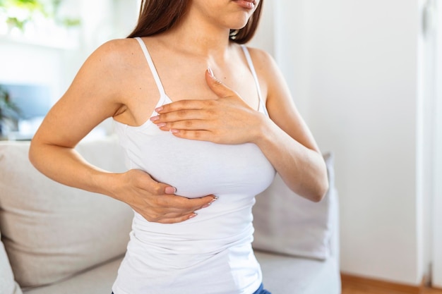 Jeune femme caucasienne palpant sa poitrine par elle-même qu'elle s'inquiète du cancer du sein Concept de soins de santé et de cancer du sein