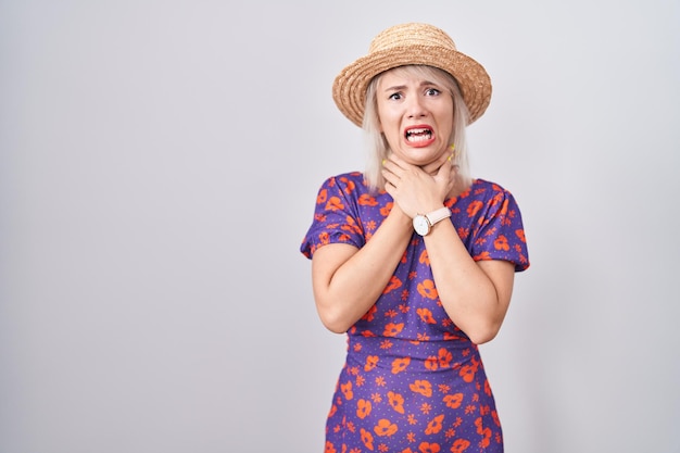 Photo gratuite jeune femme caucasienne portant une robe à fleurs et un chapeau d'été criant suffoquer parce que le problème de santé d'étranglement douloureux asphyxie et le concept de suicide