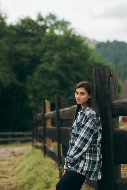 Une jeune femme caucasienne séduisante se tient près d'une clôture et se pose à la caméra