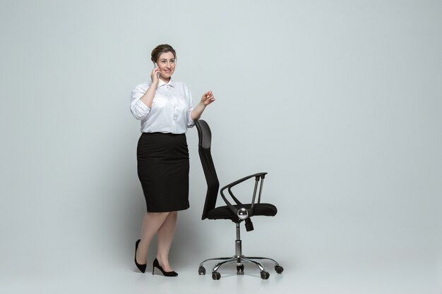 Jeune femme caucasienne en tenue décontractée sur gris. Personnage féminin Bodypositive, plus la taille