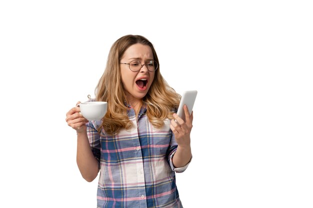 Jeune femme caucasienne utilisant un smartphone, des appareils, des gadgets isolés sur un mur blanc. Concept de technologies modernes, gadgets, technologie, émotions, publicité. Espace de copie.