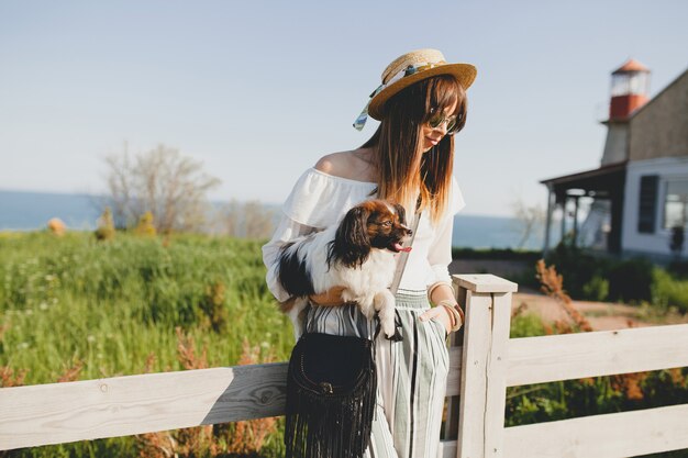 Jeune femme avec chapeau de paille avec son chien par la clôture à la campagne