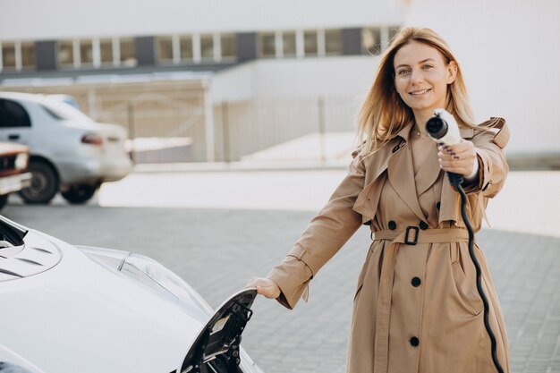 Jeune femme chargeant sa voiture électrique avec un pistolet de charge