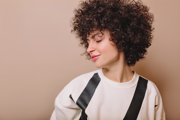 Jeune femme charmante avec une beauté naturelle et un maquillage nude sur fond beige a fermé les yeux et profite de la vie