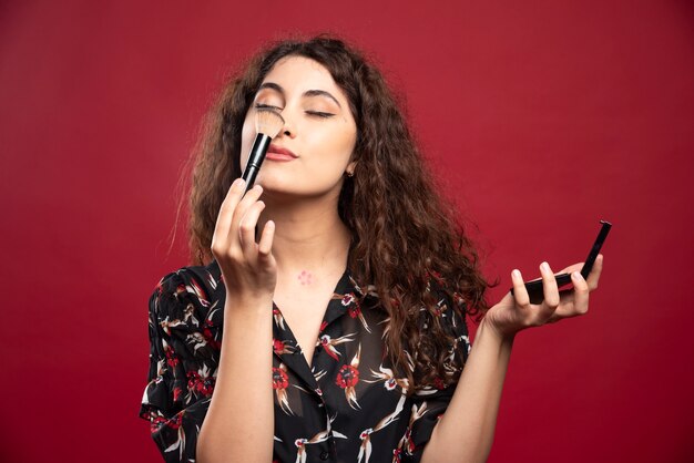 Jeune femme chatouille son nez avec pompon.