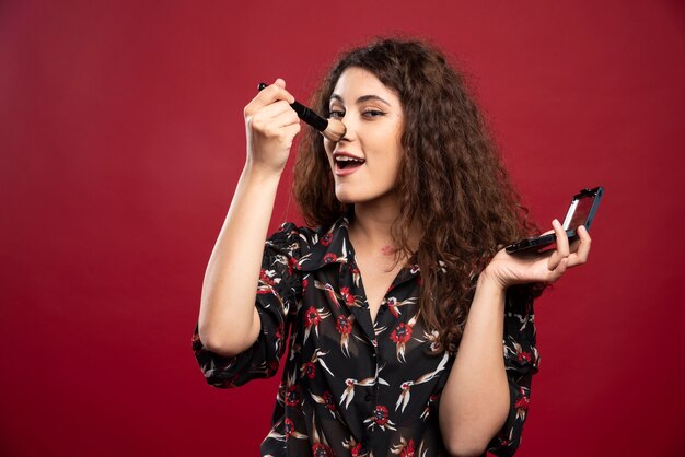 Jeune femme chatouille son nez avec pompon.