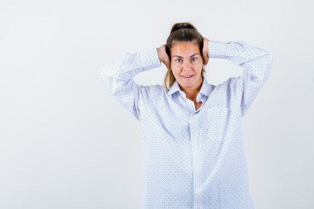 Jeune femme en chemise blanche en appuyant sur les mains sur les oreilles et à la recherche de plaisir