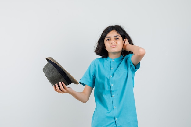 Jeune femme en chemise bleue, chapeau décollant son chapeau et à l'insatisfaction