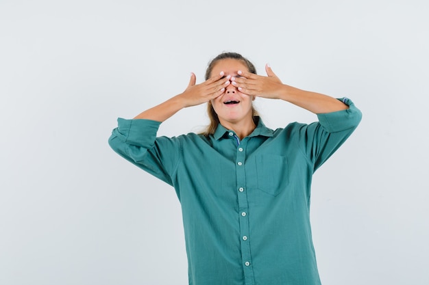 Jeune femme en chemise bleue couvrant les yeux avec les mains et l'air excité