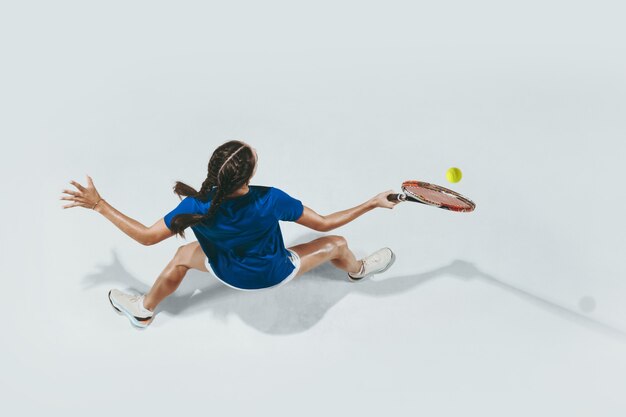 Jeune femme en chemise bleue jouant au tennis. Vue de dessus.