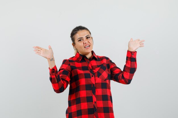 Jeune femme en chemise à carreaux faisant un geste de remise