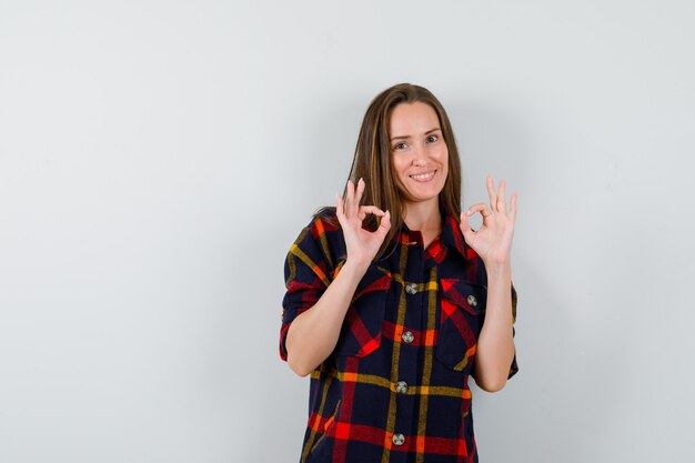 Jeune femme en chemise décontractée montrant le geste ok et à la vue de face, heureux.