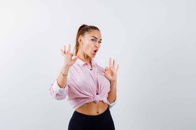 Jeune femme en chemise décontractée, pantalon montrant un geste correct et à la vue de face, heureux.