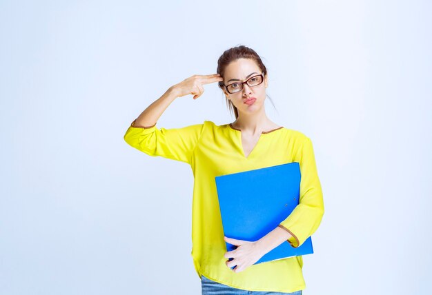 La jeune femme en chemise jaune a l'air réfléchie et rêveuse