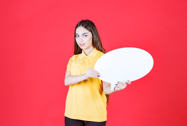 Jeune femme en chemise jaune tenant un panneau d'information ovale
