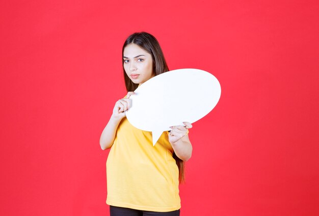 Jeune femme en chemise jaune tenant un panneau d'information ovale