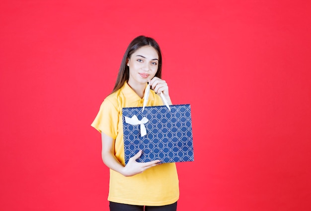 Jeune femme en chemise jaune tenant un sac bleu