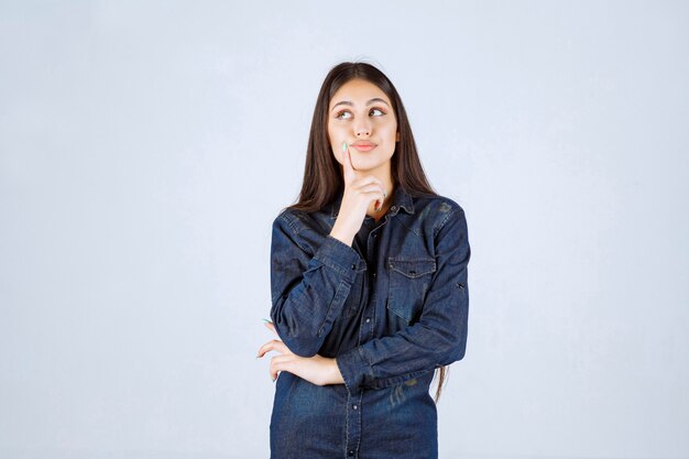 Jeune femme en chemise en jean a l'air confuse et réfléchie