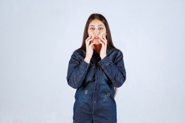 Jeune femme en chemise en jean a l'air confuse et réfléchie