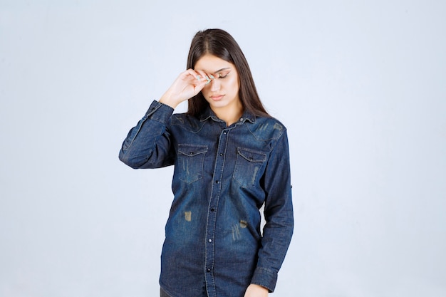 Jeune femme en chemise en jean a l'air épuisée et somnolente