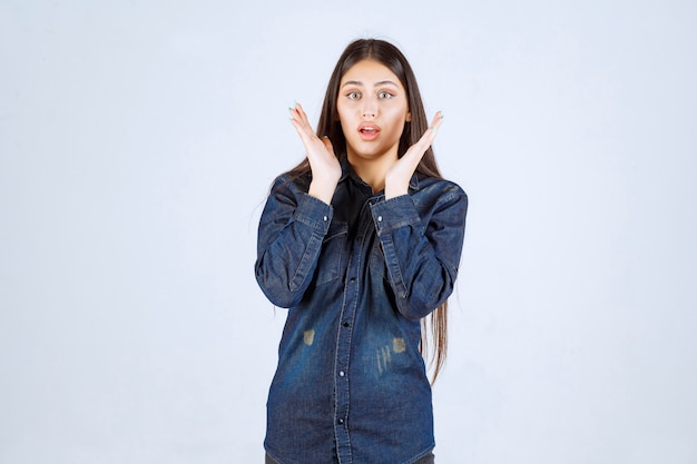 Jeune femme en chemise en jean a l'air surpris et excité